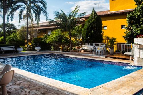 a swimming pool in a yard with a yellow house at Pousada Shangrila in Ribeirão Preto