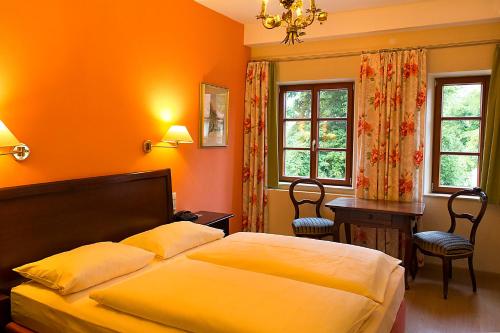 a bedroom with a bed and two windows at Hotel Reichs-Küchenmeister in Rothenburg ob der Tauber