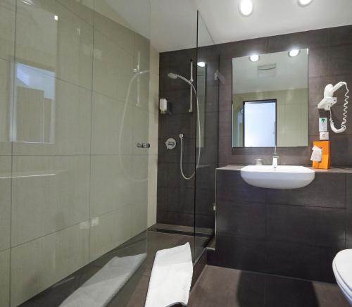 a bathroom with a sink and a shower with a mirror at Hotel Silicium in Höhr-Grenzhausen