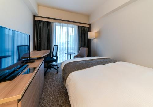 a hotel room with a bed and a flat screen tv at Daiwa Roynet Hotel Chiba-chuo in Chiba