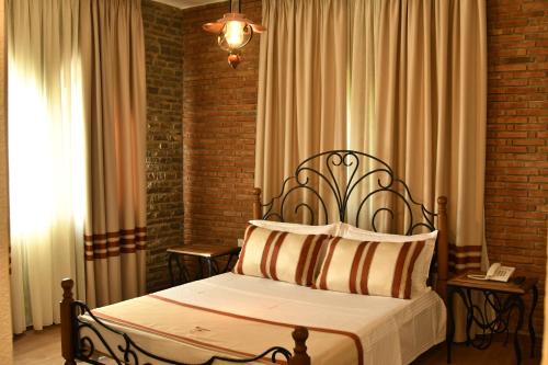 a bedroom with a bed and a brick wall at Hotel Restaurant Emblema in Petrelë