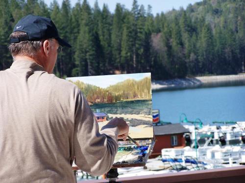 a man is painting a picture of a boat at The Pines Resort & Conference Center in Bass Lake