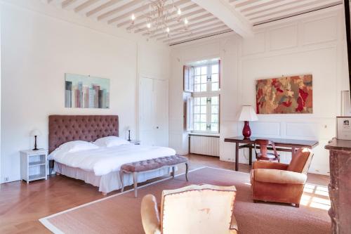 een witte slaapkamer met een bed en een stoel bij Château de la Cour Senlisse in Senlisse