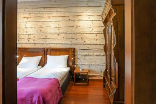 1 dormitorio con 1 cama y pared de madera en Pensjonat Maria 2, en Szczyrk