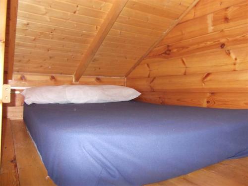 a bed in a cabin with a wooden ceiling at Cabañas Camping Sierra de Peñascosa in Peñascosa