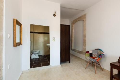 a bathroom with a toilet and a chair at Erato House in Koúfi