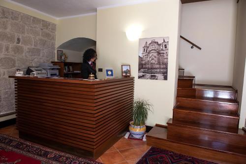 une femme assise sur un bureau dans une pièce avec des escaliers dans l'établissement Hotel Residenza Petra, à Petralia Soprana