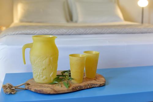un vaso giallo e due tazze su un tavolo con un letto di Mavres Luxury Loft ad Ágios Matthaíos