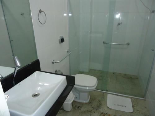 a bathroom with a toilet, sink, and shower stall at Hotel Turista in Belo Horizonte