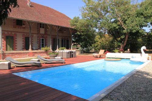 ein Pool mit Stühlen und ein Schwan im Hof in der Unterkunft Gîte la Prunéloise in Lafitte-sur-Lot