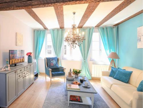 una sala de estar con cortinas azules y una lámpara de araña. en My Sweet Homes - Le 15, en Colmar