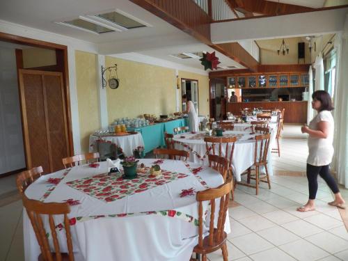 a woman standing in front of a dining room with tables at Pousada Recanto Feliz Itatiba in Itatiba