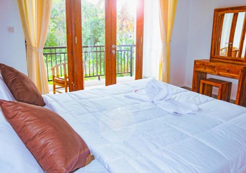 a large white bed in a room with a balcony at Kailash Homestay in Padangbai