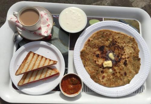 a tray with a plate of food and a cup of coffee at Hotel Shivaay Grand in Amritsar