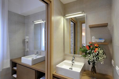 Baño con 2 lavabos, espejo y flores en Hotel Nettuno, en Caorle