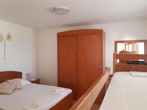 una camera con 2 letti e un armadio in legno di Apartments Denis a Metajna