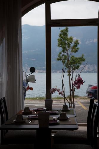 a table with flowers and a view of the water at Piccolo Hotel Direkt am See in Brenzone sul Garda