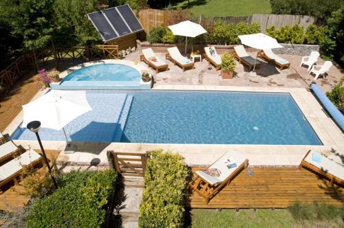 a swimming pool with chairs and umbrellas next to a pool at Cabanas Luces el Bosque in Mar de las Pampas