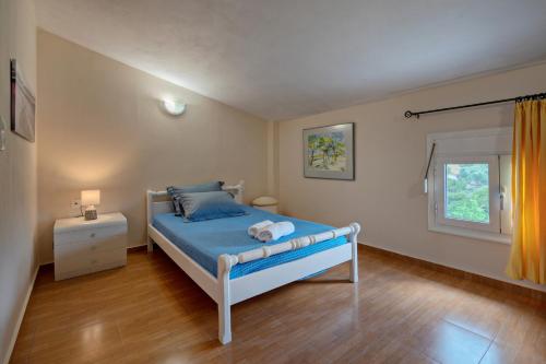 a bedroom with a blue bed and a window at Aliki Serenity Cottage in Mixórrouma