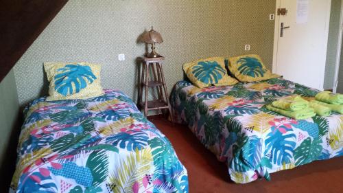 - une chambre avec deux lits et un couvre-lit avec feuilles de palmier dans l'établissement Le Curieux de Conques, à Saint-Cyprien-sur-Dourdou