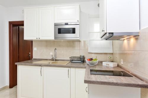 a white kitchen with a sink and a microwave at Apartments Maritea in Vodice