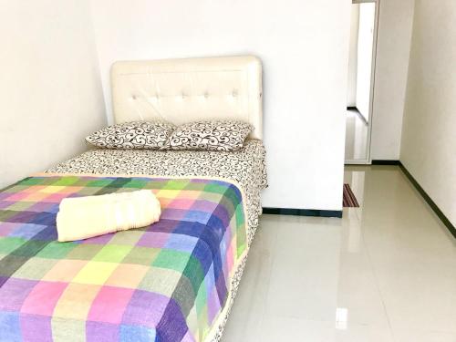a bedroom with a bed with a colorful blanket at LG Homestay in Kepanjen