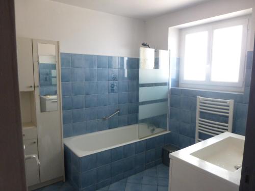 La Chapelle-AubareilにあるLa Galinieの青いタイル張りのバスルーム(バスタブ、シンク付)