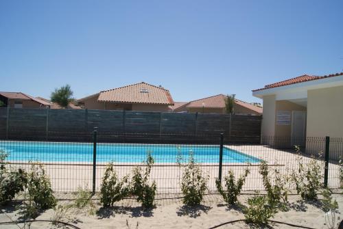比斯卡羅斯海灘的住宿－Maison Indigo 6 personnes，房屋前围栏后面的游泳池