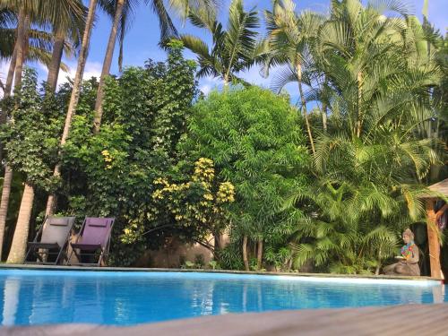 a woman standing next to a swimming pool with palm trees at Villa Oté in LʼEntre-Deux