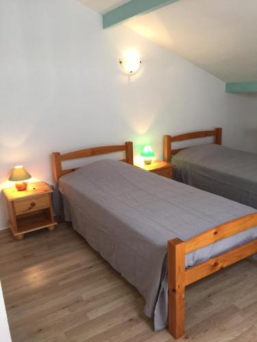 比斯卡羅斯海灘的住宿－Maison Indigo 6 personnes，配有两张床铺的房间,桌子上放着两盏灯