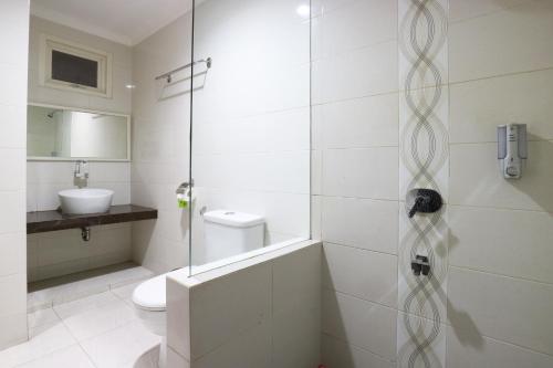 a bathroom with a shower with a toilet and a sink at Chiaro Hotel Syariah in Sidoarjo