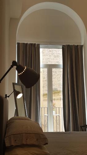 a bedroom with a lamp and a bed and a window at MammaDada charm rooms in Bari