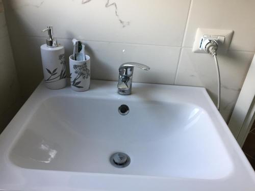 a white sink with two toothbrushes in cups on it at SoleLuna House in Modica