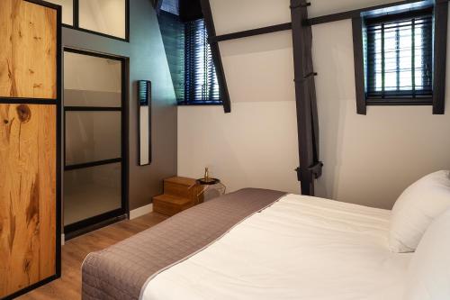 a bedroom with a white bed and some windows at Hotel Julien in Den Bosch