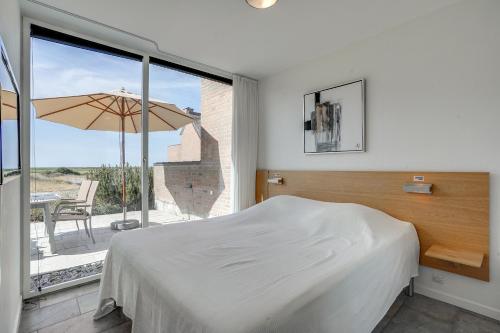 a bedroom with a bed and a patio with an umbrella at Gulirisvej Havneby Rømø in Rømø Kirkeby