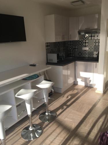une cuisine avec des comptoirs et des tabourets blancs dans l'établissement Studio Face Mer, à Le Touquet-Paris-Plage