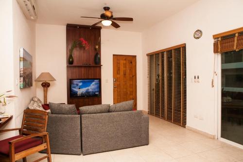 Una sala de estar con un sofá y un ventilador de techo. en Las Olas Condominium #207, en Playa del Carmen