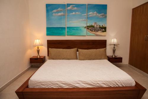 Un dormitorio con una cama con tres cuadros en la pared. en Las Olas Condominium #207, en Playa del Carmen
