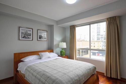 1 dormitorio con cama y ventana grande en Departamento en San Isidro, Lima, en Lima