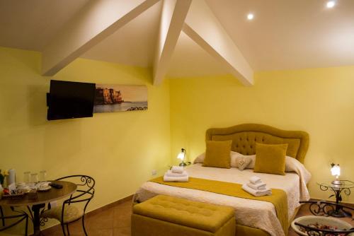 ナポリにあるLa Gemmaのベッドルーム1室(黄色い壁のベッド1台、テレビ付)