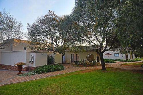 a large white house with a tree in the yard at Andante Lodge in Pretoria