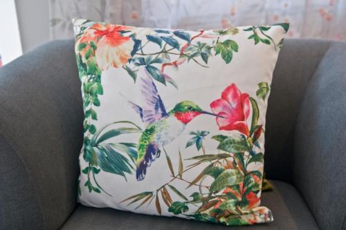a hummingbird pillow on a couch with a flower at Loft Orchidee in Überlingen