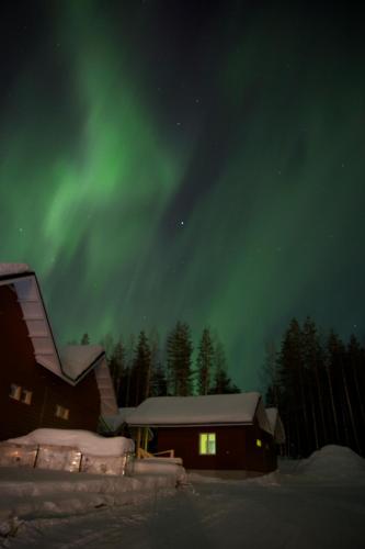 a house with the aurora in the sky at night at Santa Claus Holiday Village in Rovaniemi