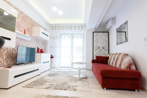 a living room with a red couch and a tv at Carla's apartment -shuttle in Iaşi
