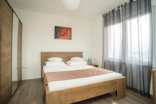 ein Schlafzimmer mit einem Bett und einem großen Fenster in der Unterkunft GardenLux Sarajevo in Sarajevo