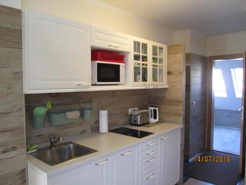 a kitchen with white cabinets and a sink and a microwave at Villa Shafaly in Mariánské Lázně