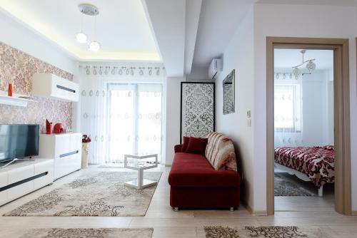 a living room with a red couch and a bed at Carla's apartment, airport & train station shuttle in Iaşi
