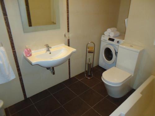 a bathroom with a toilet and a sink and a washing machine at Shamrock Flats in Mellieħa