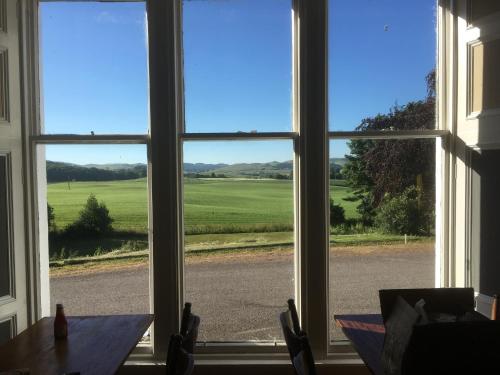 a view from a window of a table looking out at a field at Ernespie House Hotel in Castle Douglas