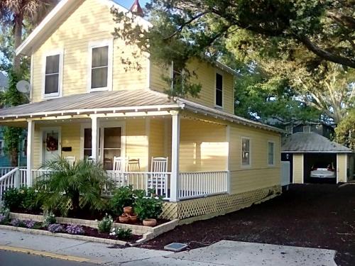 a yellow house with a front porch and a yard at Villa Riberia in St. Augustine